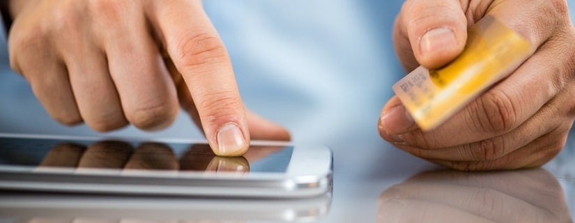 Une personne effectuant une transaction en ligne avec une tablette et une carte de crédit à la main